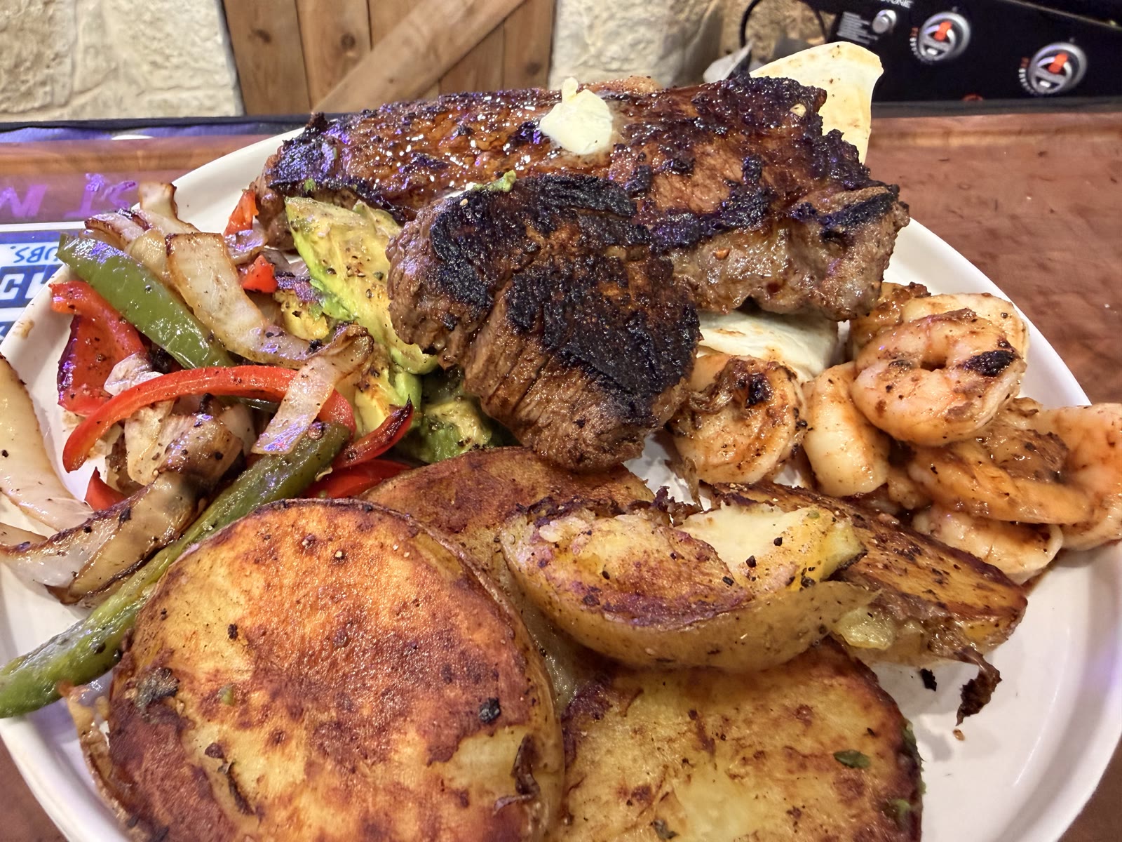 Plated 30-minute surf and turf - ribeye, BBQ shrimp, grilled potatoes, charred Texas veggies and avocado